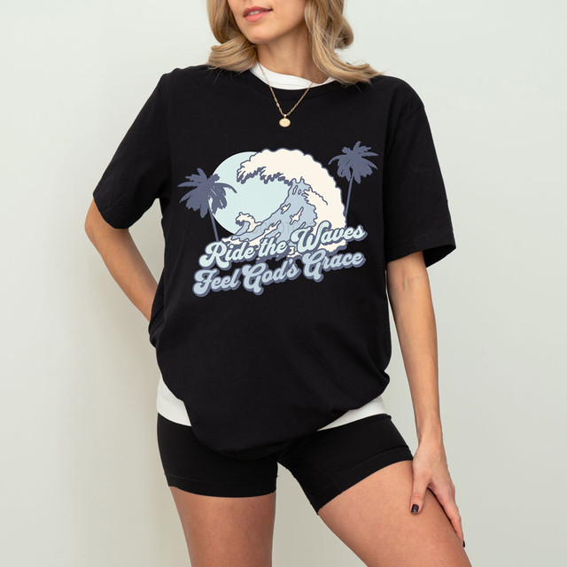 Ride The Waves Feel God's Grace DTF Heat Transfer on a woman's graphic t-shirt with ocean wave, palm trees, and inspirational text design.