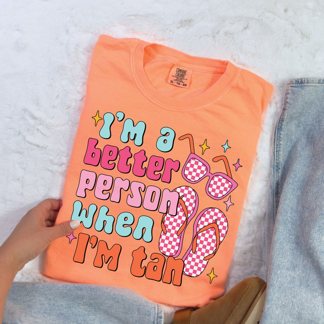 I'm A Better Person When I'm Tan Retro DTF Heat Transfer, peach-colored t-shirt with pink, purple, blue, and orange text and checkered sunglasses and flip-flops design.