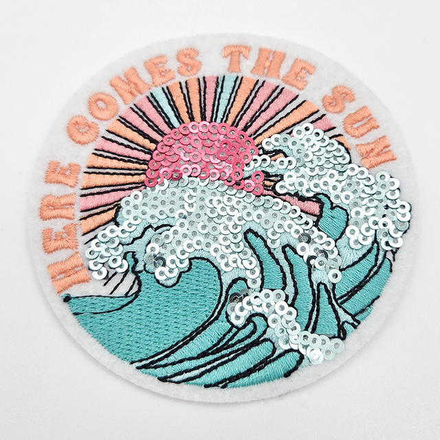 Here Comes The Sun SEQUIN & Embroidered HAT/POCKET Patch, a round patch featuring a sunburst design with embroidered rays, sequined waves, and clouds with a pink sun, perfect for decorating hats or pockets.