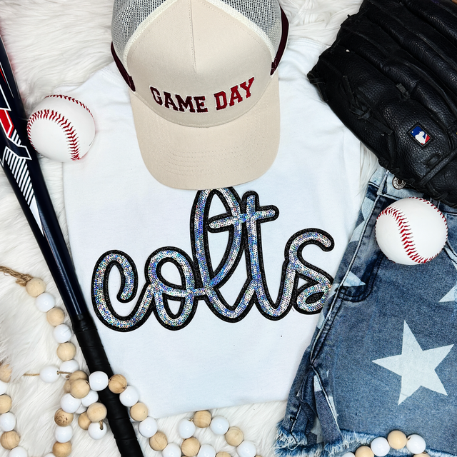 Colts Sequin Patch, close-up of a sequin patch spelling 'eat' on a white shirt with baseball-themed accessories and apparel.