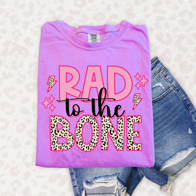 Rad To The Bone DTF Heat Transfer, pink T-shirt with 'Rad to the Bone' graphic in bold, leopard print and pink text, decorated with lightning bolts and star accents.