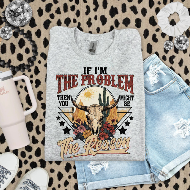 If I'm The Problem You Might Be The Reason Western DTF Heat Transfer, gray T-shirt featuring a design with a skull of a longhorn steer, cactus, sun, flowers, and stars on leopard print background.