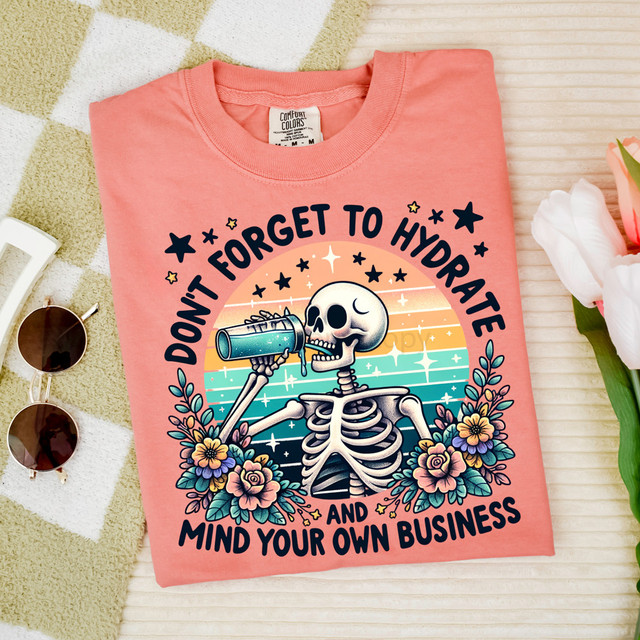 Don't Forget To Hydrate Skeleton DTF Heat Transfer, a colorful skeleton graphic wearing sunglasses and holding a telescope, surrounded by flowers and stars on a pink T-shirt.