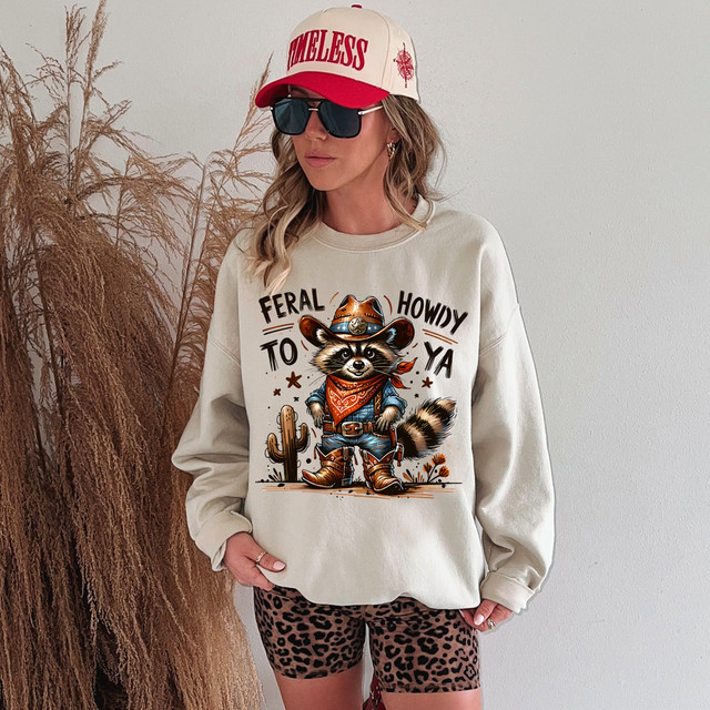 Feral Howdy To Ya DTF Heat Transfer, featuring a cartoon raccoon dressed as a cowboy with a background of desert plants.