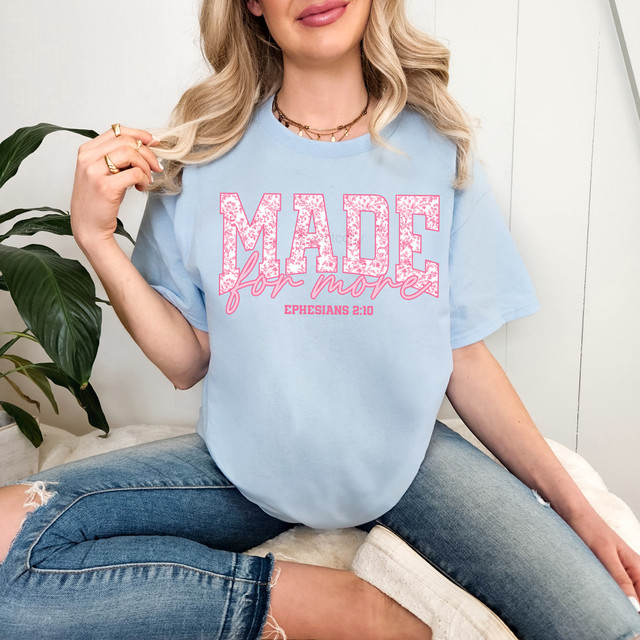 Made For More Pink Toile DTF Heat Transfer, a pink floral design text on a light blue t-shirt worn by a woman.