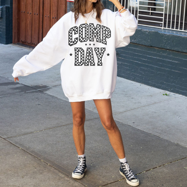 Comp Day Checkered DTF Heat Transfer, a black and white checkered design on a large white sweatshirt worn by a woman