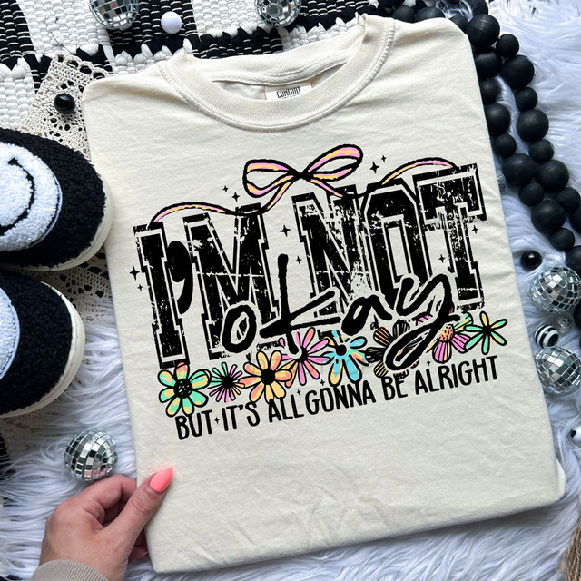I'm Not Okay But It's Gonna Be Alright Retro DTF Heat Transfer T-shirt, beige shirt with colorful floral and distressed text design.