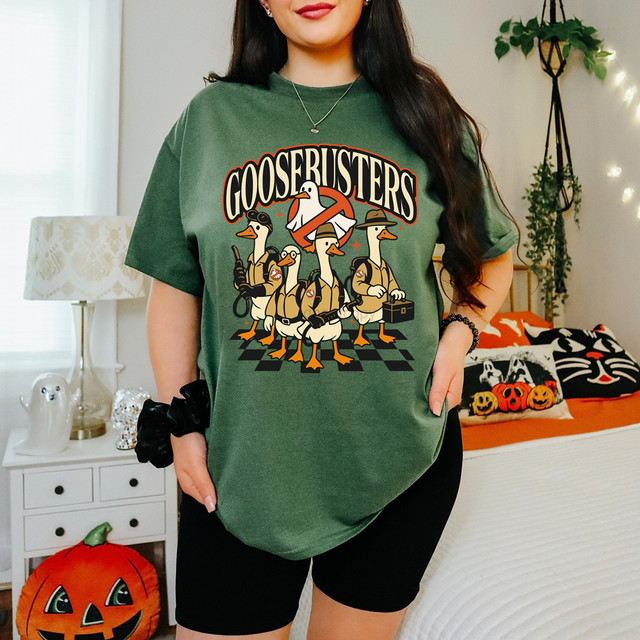Goosebusters Halloween DTF Heat Transfer, graphic t-shirt featuring cartoon geese dressed as Ghostbusters characters in a spooky scene.