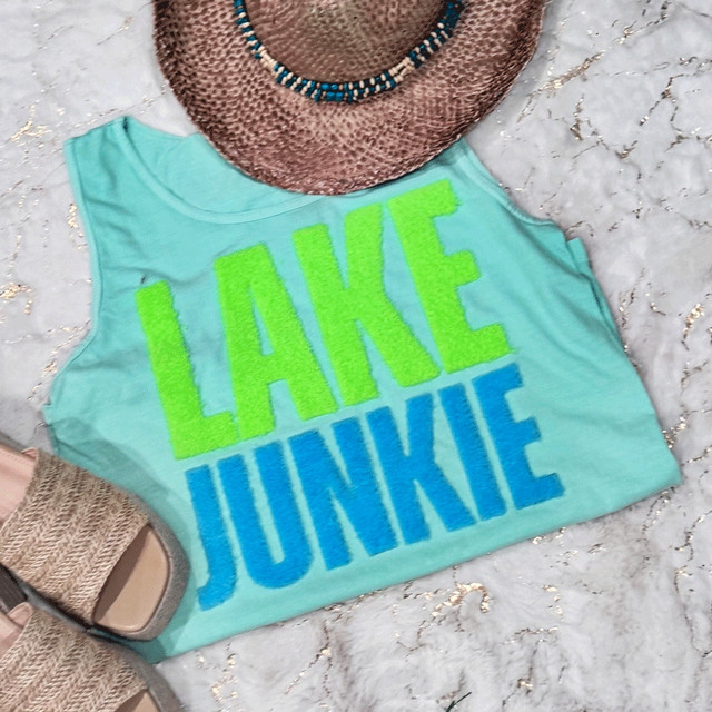 Lake Junkie Fluffy Patch, bright green and blue fluffy letter patches on a light blue sleeveless top.