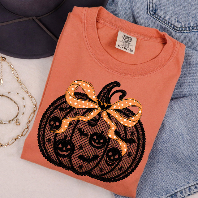 Faux Lace Pumpkin DTF Heat Transfer, orange T-shirt with Halloween pumpkin design featuring lace pattern, bow, and spooky faces.
