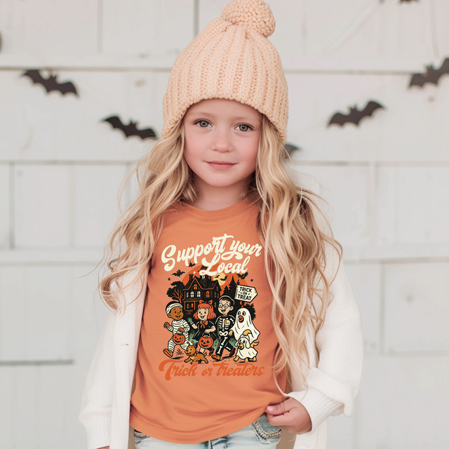 Support Your Local Trick Or Treaters CREAM DTF Heat Transfer, image of a young girl wearing a Halloween-themed t-shirt with fun October characters, pumpkins, and bats for trick or treating.
