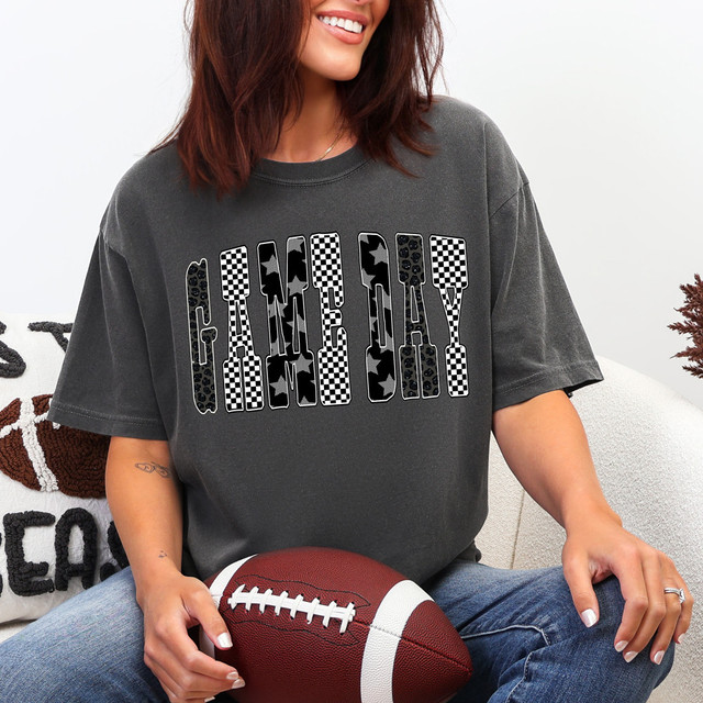 Patterned Game Day DTF Heat Transfer, product featuring a woman wearing a dark gray T-shirt with black and white checkered and star patterns in the letters spelling 'GAME DAY'.