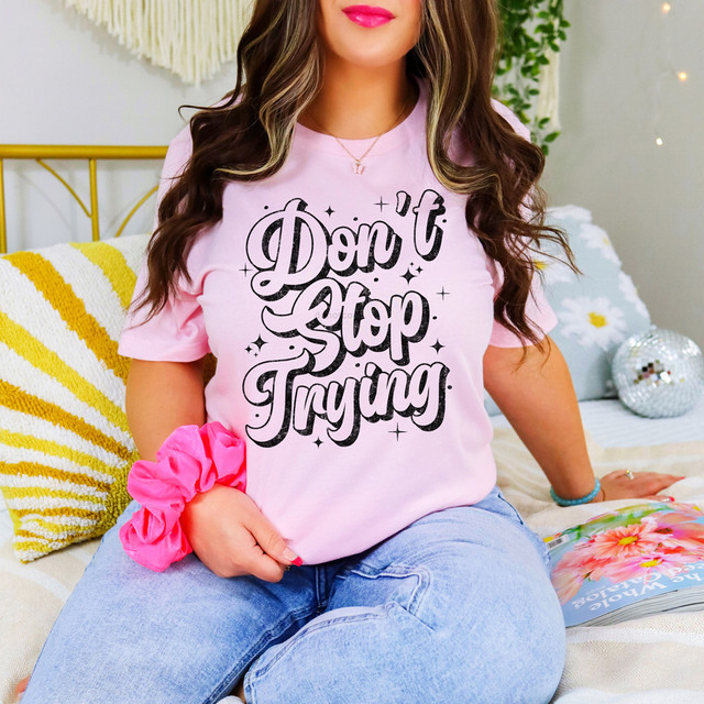 Don't Stop Trying DTF Heat Transfer, close-up of a woman wearing a pink T-shirt with the uplifting message 'Don't Stop Trying' printed in bold black letters, used for custom clothing decoration.