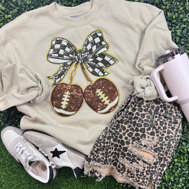 Football Cherries with Checkered Bow Patch, clothing and accessories display with sweatshirt, ripped leopard print shorts, sneakers, and a tumbler.