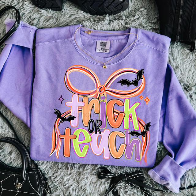 Trick or Teach DTF Heat Transfer, colorful Halloween-themed design on purple sweatshirt with bat and bow decorations for fall apparel