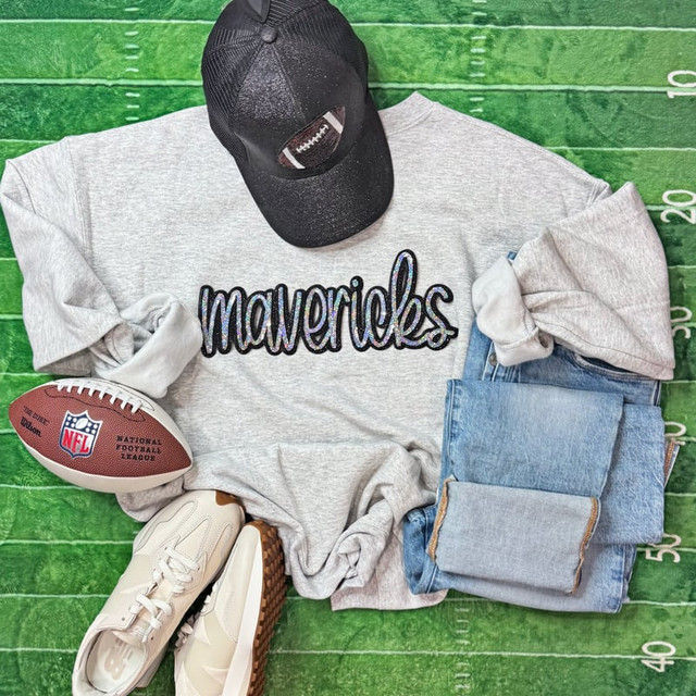 Mavericks Sequin Patch, stylish casual outfit including a grey sweatshirt with Mavericks logo, denim jeans, a black baseball cap, white sneakers, and an NFL football, arranged on a green football field background.