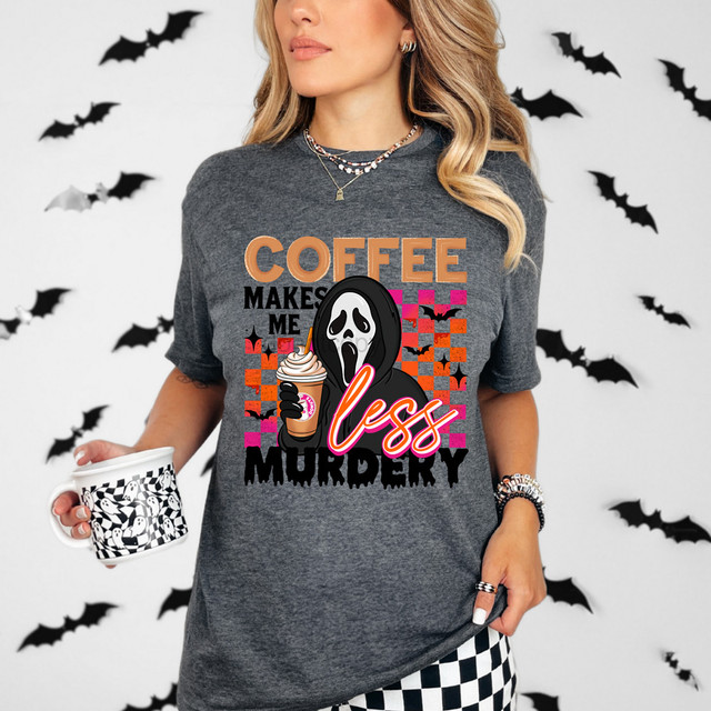 Coffee Makes Me Less Murdery Dunkin DTF Heat Transfer, graphic T-shirt with a spooky ghost holding coffee, with Halloween-themed background and accessories.