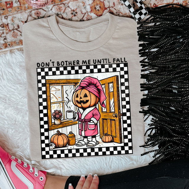Don't Bother Me Until Fall DTF Heat Transfer, illustrated Halloween-themed pumpkin character with a coffee mug, standing by an open door with pumpkins and fall decor inside, surrounded by a checkered border.