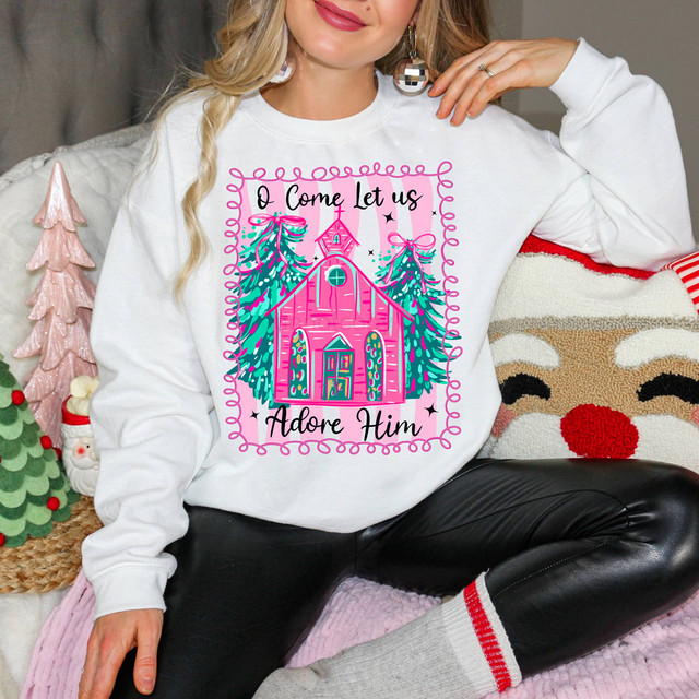 O Come Let Us Adore Him Pink Church DTF Heat Transfer, Christmas-themed sweatshirt featuring a pink church with two Christmas trees and festive decorations.
