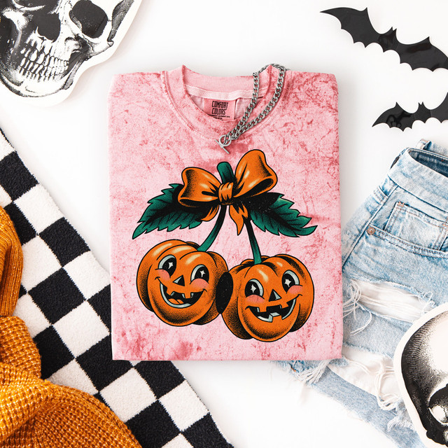 Grunge Pumpkin Cherries DTF Heat Transfer, pink T-shirt with illustrations of two smiling pumpkins with faces, topped with a orange bow and green leaves.
