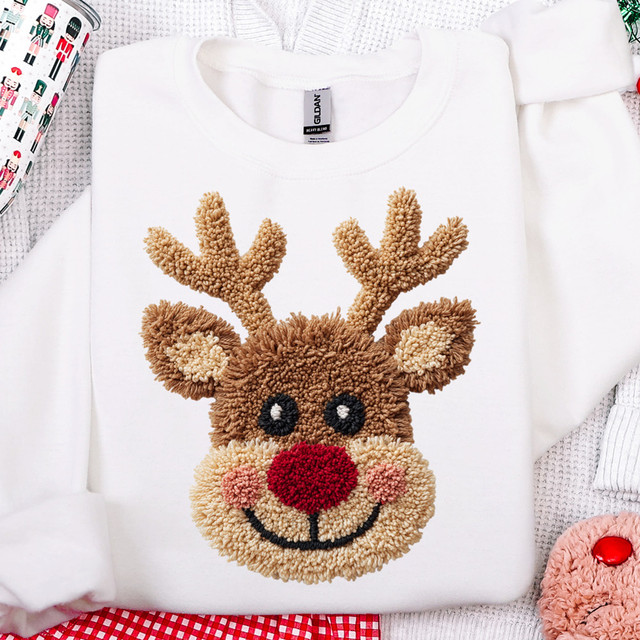 Faux Crochet Reindeer DTF Heat Transfer, a cute reindeer face with a red nose and antlers embroidered with soft, plush faux crochet material on a white sweatshirt.