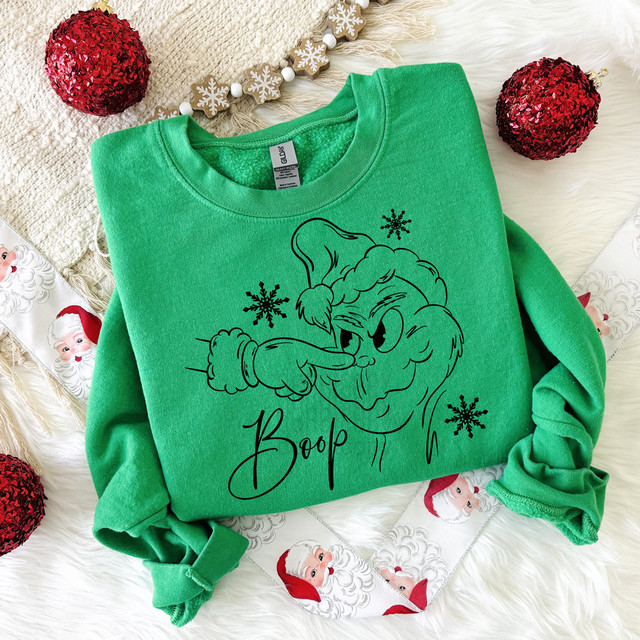 Boop Green Guy BLACK DTF Heat Transfer, black cartoon character design with Santa hat on a green sweatshirt surrounded by Christmas decorations.