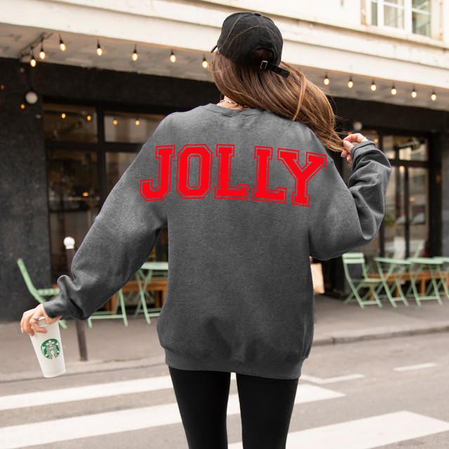 Oversized Jolly BUNDLE DTF Heat Transfer, a person wearing a gray sweatshirt with the word JOLLY in red letters on the back, standing outdoors in an urban setting.