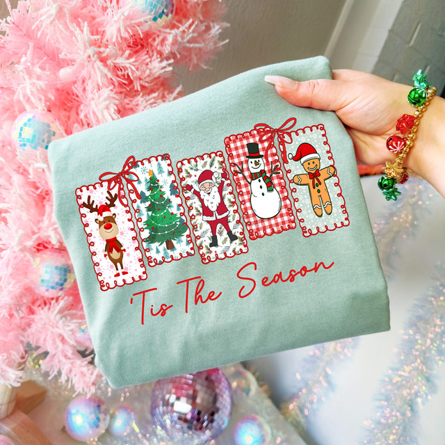 Tis The Season Christmas Favorites DTF Heat Transfer, festive holiday sweatshirt with Christmas-themed characters including a reindeer, Christmas tree, Santa Claus, snowman, and gingerbread man.