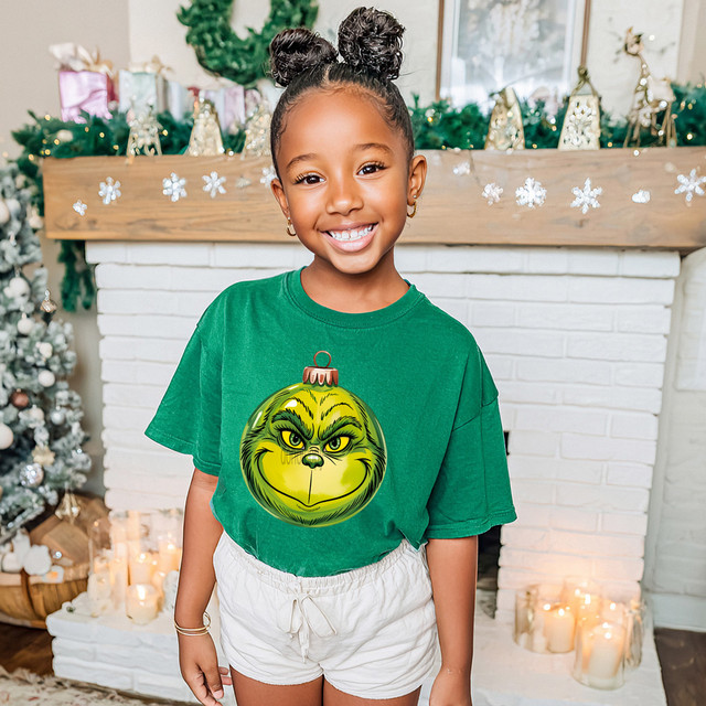Green Guy Ornament DTF Heat Transfer, festive Christmas ornament design on a smiling girl's green t-shirt.