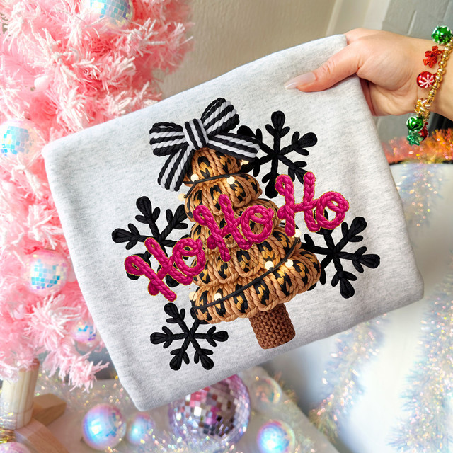 Faux Yarn Ho Ho Ho Tree DTF Heat Transfer, a colorful embroidered design featuring a holiday tree with pink 'ho ho ho' lettering, surrounded by black snowflakes on a gray fabric background.