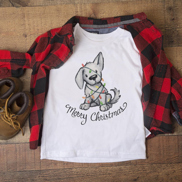 Christmas Puppy with Lights Sublimation Transfer, festive cartoon puppy wearing Christmas lights on a white t-shirt with 'Merry Christmas' text, surrounded by plaid shirt and boots.