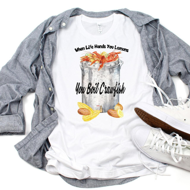 When Life Hands You Lemons Boil Crawfish sublimation transfer on a white T-shirt with seafood graphics, surrounded by a gray shirt and white shoes.