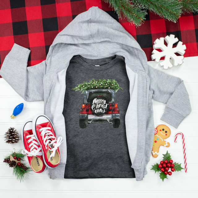 Christmas Jeep Youth Screen Print Heat Transfer, a graphic of a car with a Christmas tree on top and 'Merry Christmas' message, on a dark grey T-shirt, surrounded by holiday decorations and clothing.