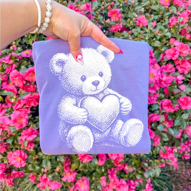 Halftone Heart Teddy Bear DTF Heat Transfer, image of a purple fabric with a white halftone teddy bear holding a heart design for heat transfer apparel decoration.