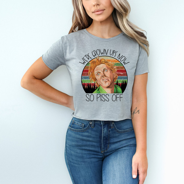 We're Grown Ups Now DDF DTF Heat Transfer, a woman wearing a gray T-shirt with a humorous graphic design featuring a woman with red hair and the text "We're Grown Ups Now So Piss Off."