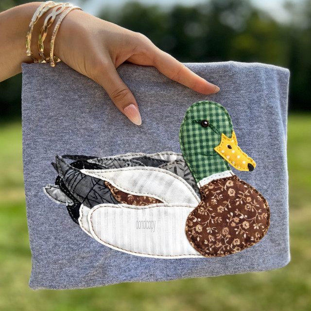 Faux Patchwork Sitting Mallard Duck DTF Heat Transfer, embroidered fabric pile quilt pattern of a mallard duck on a gray fabric surface.