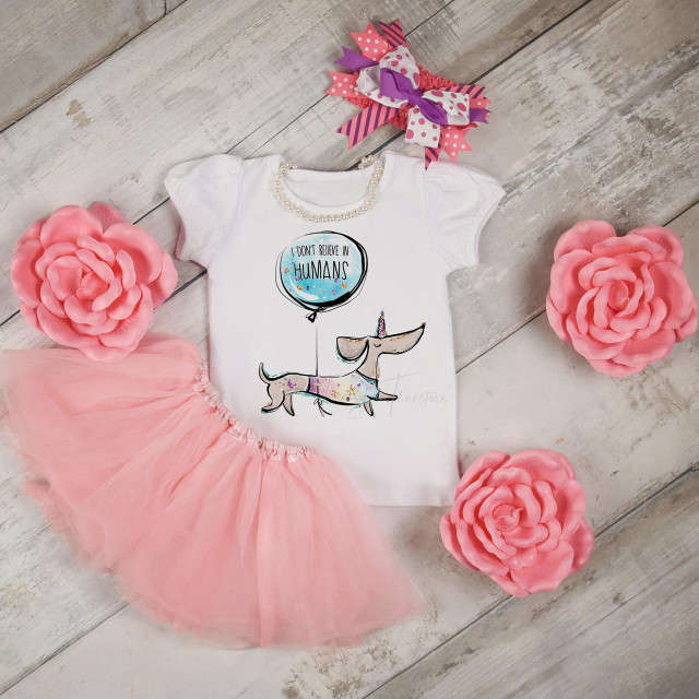 I Don't Believe In Humans Weiner Dog Dachshund Sublimation Transfer, adorable white t-shirt with dachshund illustration and quote, surrounded by pink tulle tutu, large pink paper flowers, and a colorful ribbon bow for pet-themed or humorous apparel design