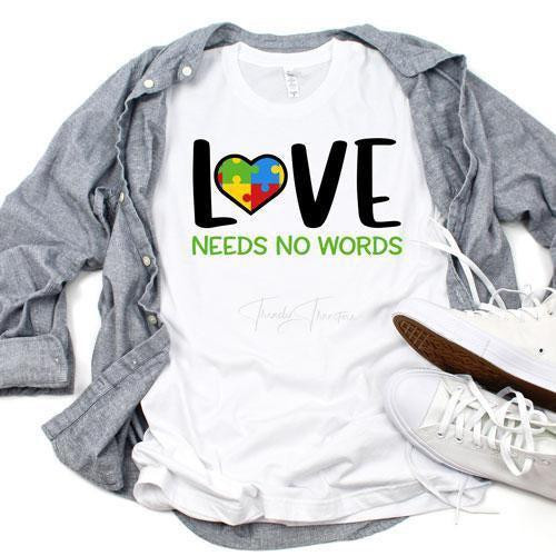 Autism Awareness Love Needs No Words Sublimation Transfer, white T-shirt with colorful heart puzzle piece and supportive message, styled with gray jacket and white sneakers.