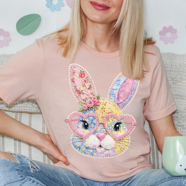 Faux Patchwork Bunny Face DTF Heat Transfer, a colorful embroidered bunny face with patchwork ears, floral details, and heart-shaped glasses on a woman wearing a pink t-shirt.