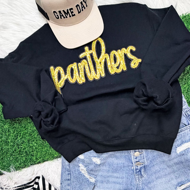 Gold sequin Panthers script mascot patch with black backing on black sweatshirt styled for game day spirit wear