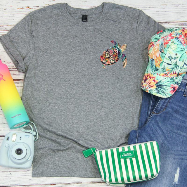 Multicolor Sea Turtle HAT/POCKET Screen Print Transfer, flat lay of a gray t-shirt with colorful sea turtle design, surrounded by casual summer accessories on a wooden background.
