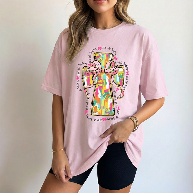 He Is Risen Easter Cross DTF Heat Transfer, colorful Easter gift box with decorative ribbon design on a pink T-shirt.