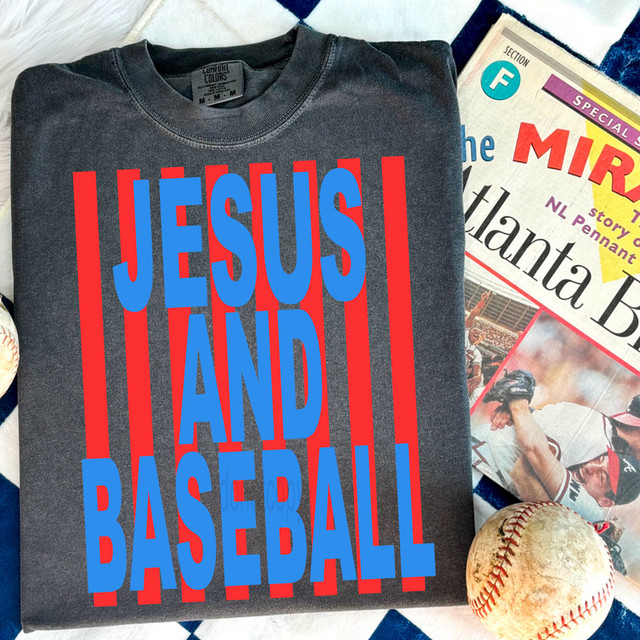 Jesus And Baseball Bold Stripe DTF Heat Transfer, a dark gray T-shirt with bold red and blue text that says 'JESUS AND BASEBALL' over red and blue stripes, surrounded by a baseball and a newspaper.