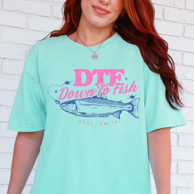 DTF Down To Fish DTF Heat Transfer, colorful graphic design featuring a fish with pink and blue text on a light teal T-shirt.