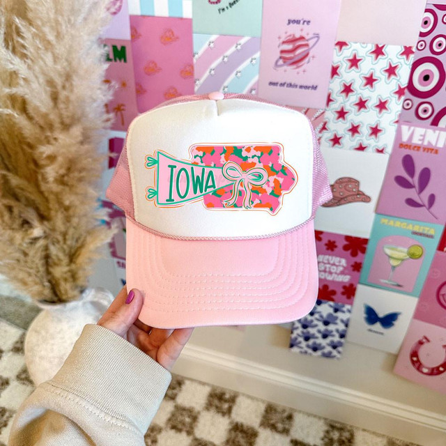 Iowa State Pride Bow DTF Heat Transfer on a pink and white trucker style cap with a camouflage outline of the state of Iowa, featuring a bow graphic.