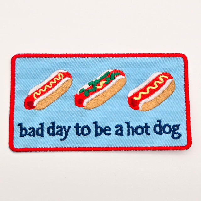 Bad Day to Be a Hot Dog – Embroidered Hat Patch, patch featuring three hot dog illustrations with humorous toppings and the phrase 'bad day to be a hot dog' embroidered at the bottom.