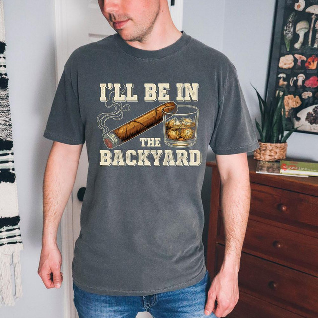I'll Be In The Backyard DTF Heat Transfer, T-shirt with a graphic of a cigar and a glass of whiskey with ice cubes.