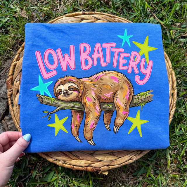 Low Battery Sloth DTF Heat Transfer, colorful sloth illustration on a blue fabric with the text 'LOW BATTERY' and star decorations.