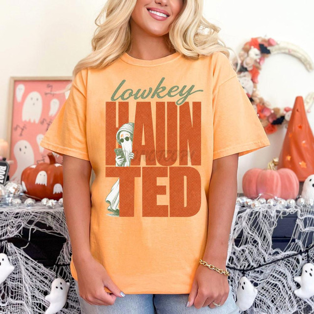 Lowkey Haunted DTF Heat Transfer, Halloween-themed graphic T-shirt with spooky ghost and pumpkin decorations in the background.
