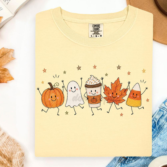 Fall Friends DTF Heat Transfer, cute illustrated fall-themed characters holding hands on a T-shirt, including a pumpkin, ghost, coffee cup, maple leaf, and candy corn.